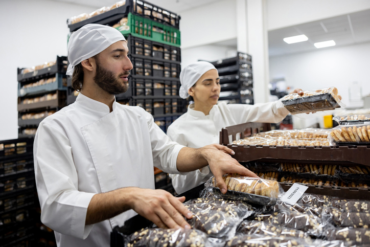 Employees at an industrial bakery getting packages of bread ready for transportation